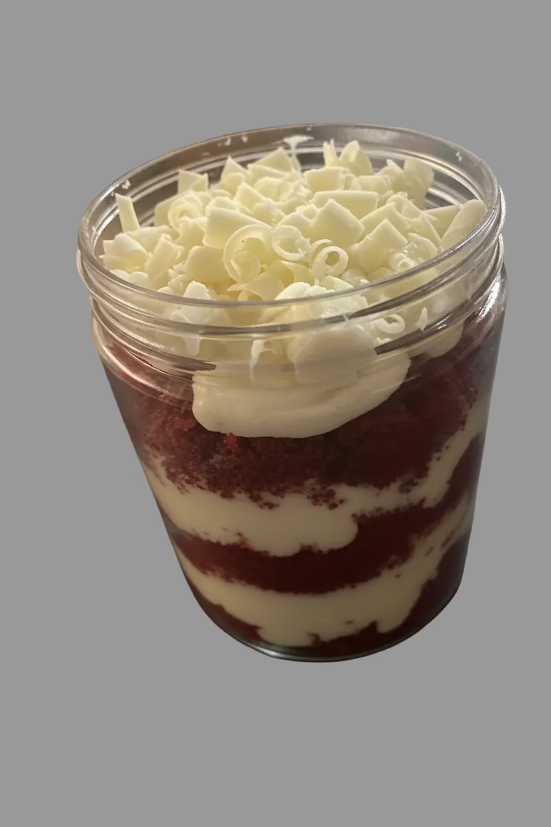 Layered dessert in a clear container on a dark surface